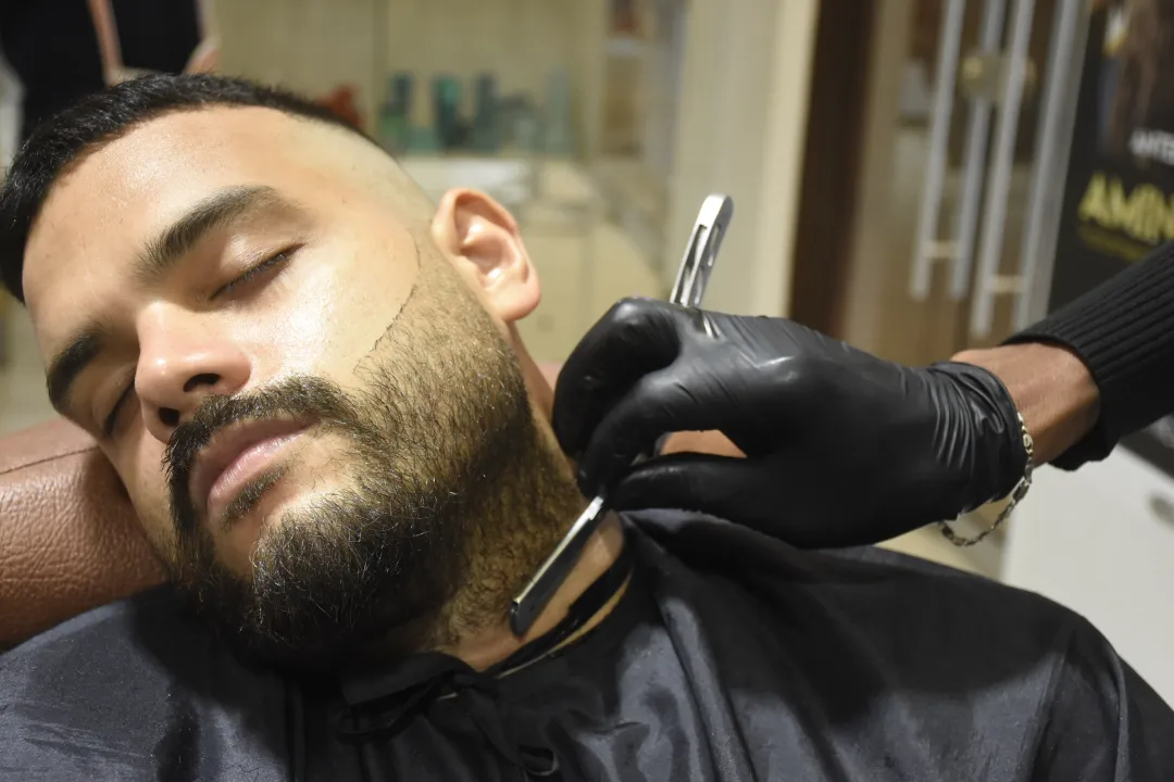 Barbero atendiendo a un cliente en la zona de barbería de Mónica Cruz en Cartagena